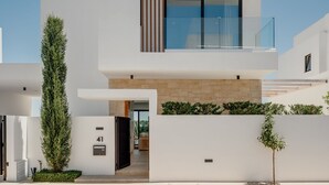 Un edificio moderno de dos pisos con un diseño minimalista, que cuenta con un amplio balcón de vidrio y fachada de piedra.