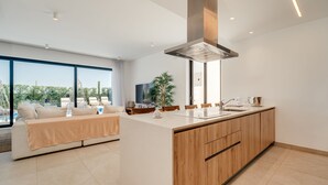 Una cocina moderna con una isla central, armarios de madera y un amplio ventanal con vistas a una piscina.