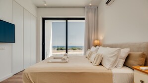 Un dormitorio moderno con una cama grande, una mesita de noche, un televisor montado en la pared y vistas al exterior a través de una puerta corredera.