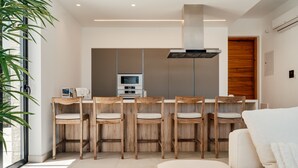Una cocina moderna con una isla central, taburetes de bar y un horno empotrado.