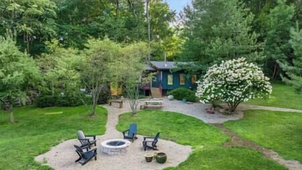 A backyard with a fire pit, outdoor seating, and a house in the background. - Beautiful Oasis | Sauna | Mohican Getaway (Perrysville)