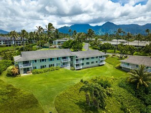 Un resort con edificios de varios pisos, un césped cuidado y montañas al fondo.