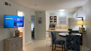 Een moderne keuken met een eetgedeelte, een flatscreen televisie aan de muur en een kleine tafel met stoelen.