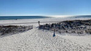 Een zandstrand met een heldere lucht en een hek op de voorgrond.