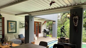 Un patio techado con una mesa de comedor, sillas y varios objetos decorativos.