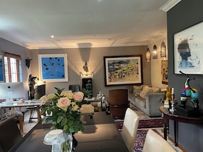 Een moderne woonkamer met een eethoek, met kunstwerken, een beeld en een kleurrijke scooter.