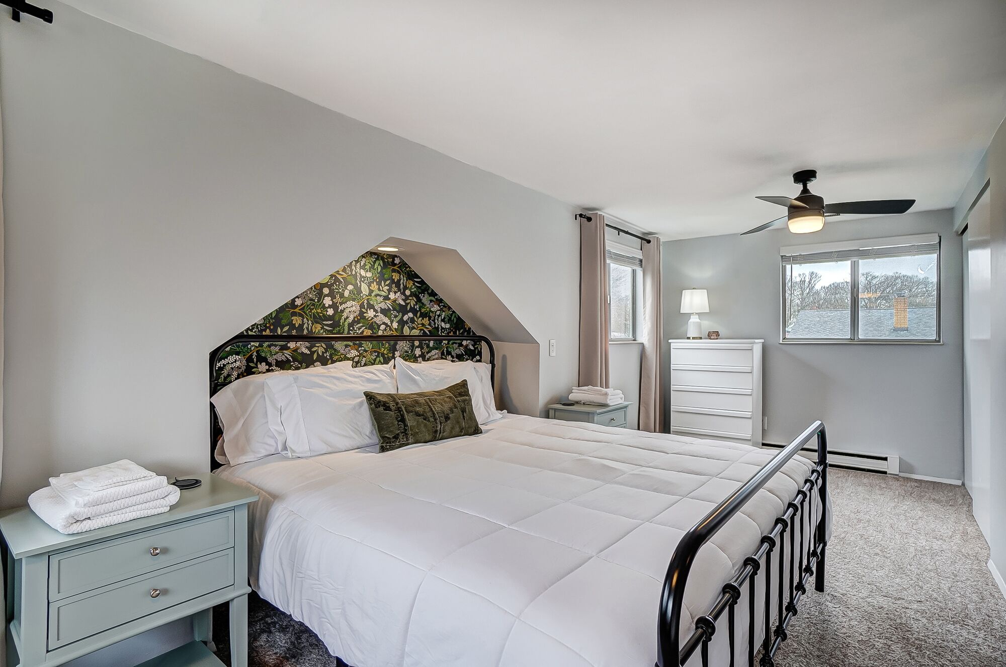 A bedroom with a bed, nightstand, dresser, and a ceiling fan.