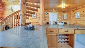 Un intérieur en bois avec un îlot central, un escalier et un coin repas.