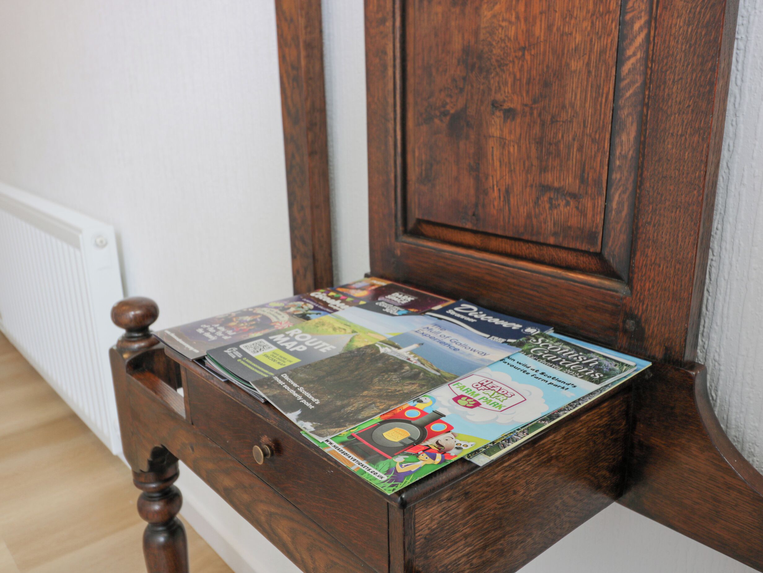 A wooden chest of drawers with a collection of magazines.