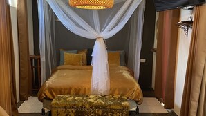 Une chambre à coucher avec un lit, une chaise, un téléviseur et un baldaquin.
