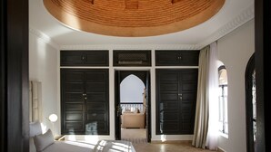 Une chambre dotée d’un grand lit, d’un plafond orné d’un motif circulaire et donnant sur un balcon.