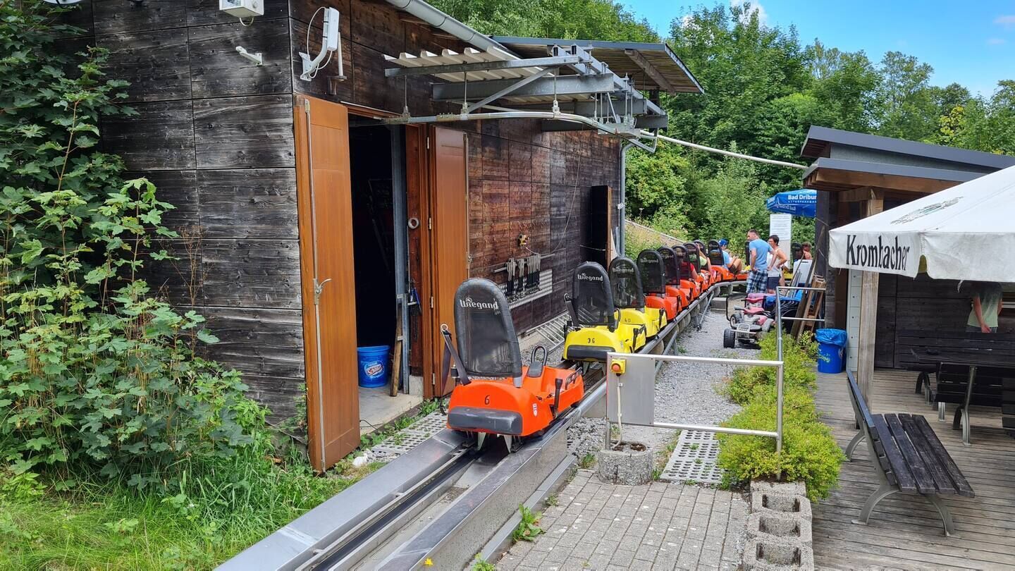 A wooden building with a covered outdoor area, a small train, and a sign that reads "Kromtacher."