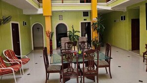 A spacious indoor area with a central table surrounded by chairs, a balcony with railings, and a flag hanging from the ceiling. - Hotel Barranquilla Inn (Barranquilla)