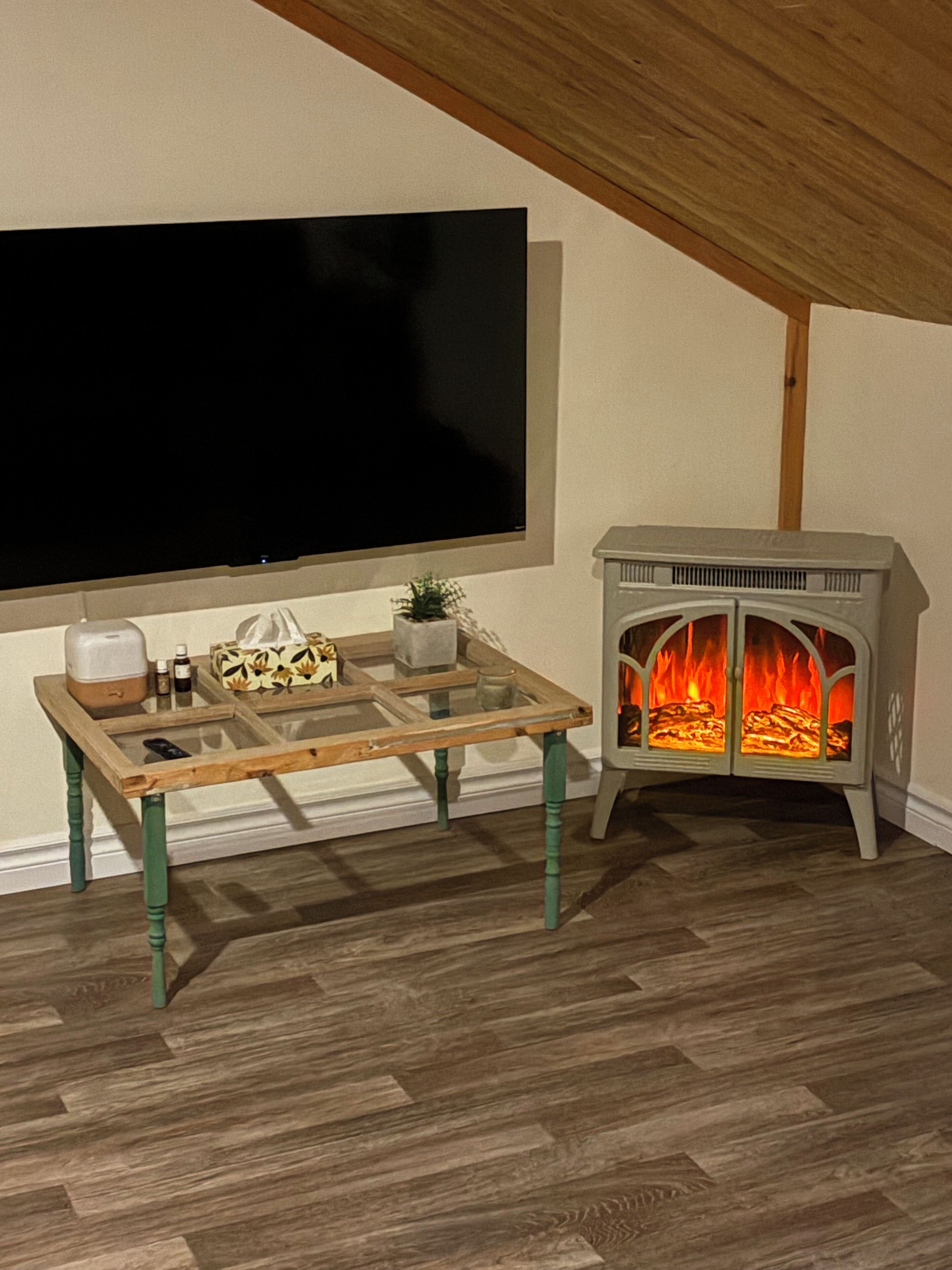 A cozy room with a wooden table, a flat-screen TV, and a wood-burning stove.