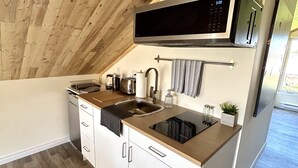 Una cucina compatta con soffitto in legno, elettrodomestici integrati e un piccolo piano di lavoro.