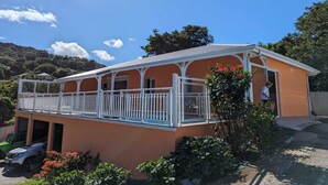 A two-story building with a balcony, surrounded by greenery and a clear sky. - Villa Tiaré Tahiti (Deshaies)