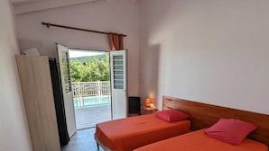 A room with two beds, a ceiling fan, a view of a balcony, and a door leading outside. - Villa Tiaré Tahiti (Deshaies)