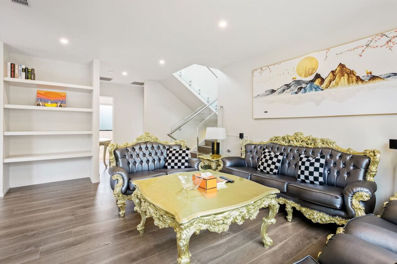 Een luxueuze woonkamer met een statige trap, een groot schilderij en een boekenkast.