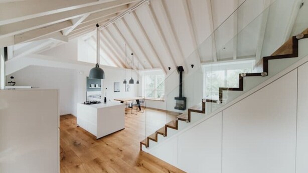 Een moderne keuken met een centraal eiland, houten vloeren en een trap naar een hoger niveau.