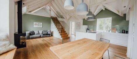 Un loft spacieux avec une table à manger en bois, un escalier et un coin cuisine.