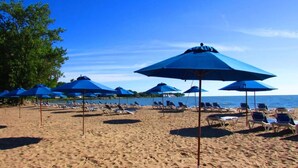 Een strand met rijen blauwe parasols en ligbedden.
