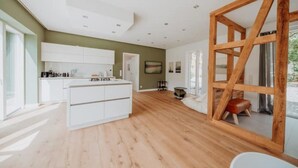 Une cuisine moderne avec des armoires blanches, un plancher en bois et une grande fenêtre.