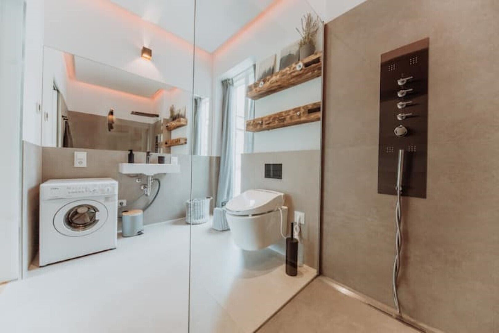 Une salle de bain moderne équipée d’un lave-linge, de toilettes et d’étagères intégrées.