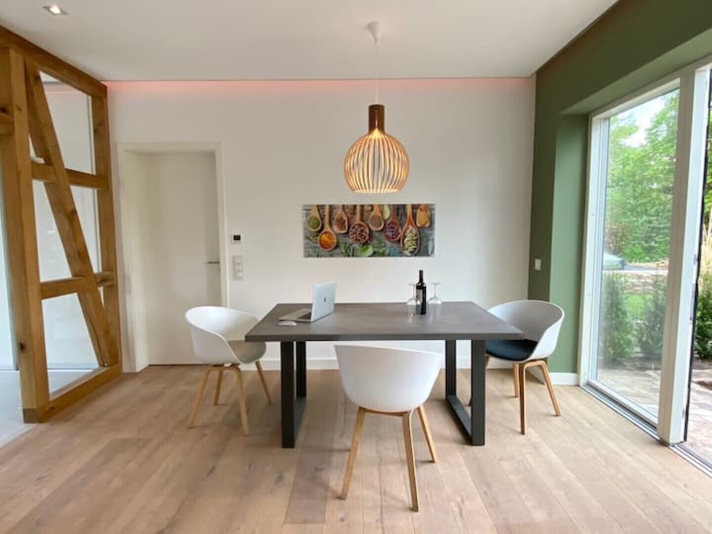 Un comedor moderno con una mesa de madera oscura, sillas blancas y una lámpara colgante original.