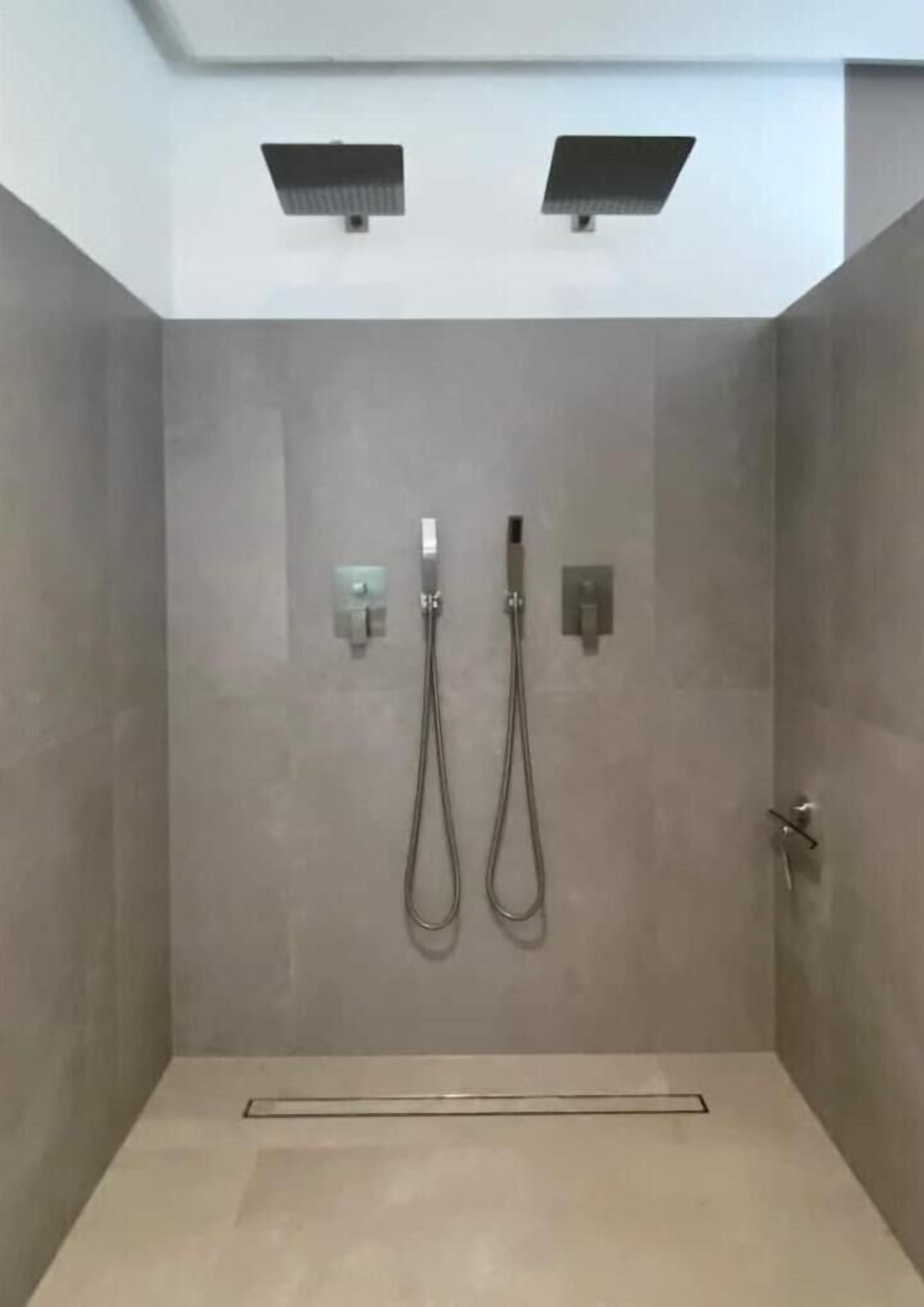 Ein moderner Duschbereich mit zwei Duschköpfen und einer Armatur an der Wand.