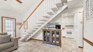 Una sala de estar moderna con una escalera, un mostrador de café y una zona de cocina.