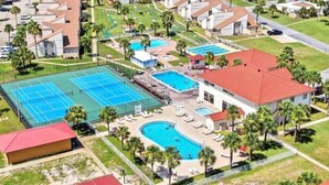Vista aérea de una zona residencial con una gran piscina, canchas de tenis y un club social.