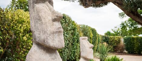 Une statue de pierre représentant une figure, placée dans un jardin.