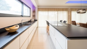 A modern kitchen with a large island, a built-in oven, and a window with a view.