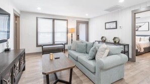A modern living room with a light blue sofa, a wooden coffee table, and a dark wooden sideboard.