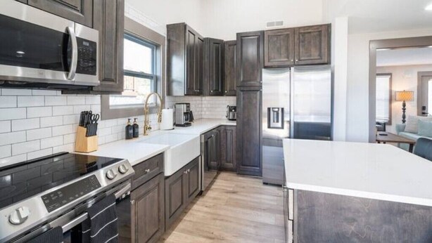 A modern kitchen with dark wood cabinets, stainless steel appliances, and a white countertop.