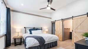 A bedroom with a bed, bedside tables, a ceiling fan, and a sliding barn-style door.