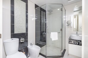 Casa de banho moderna com cabine de duche em vidro, lavatório branco e sanita.