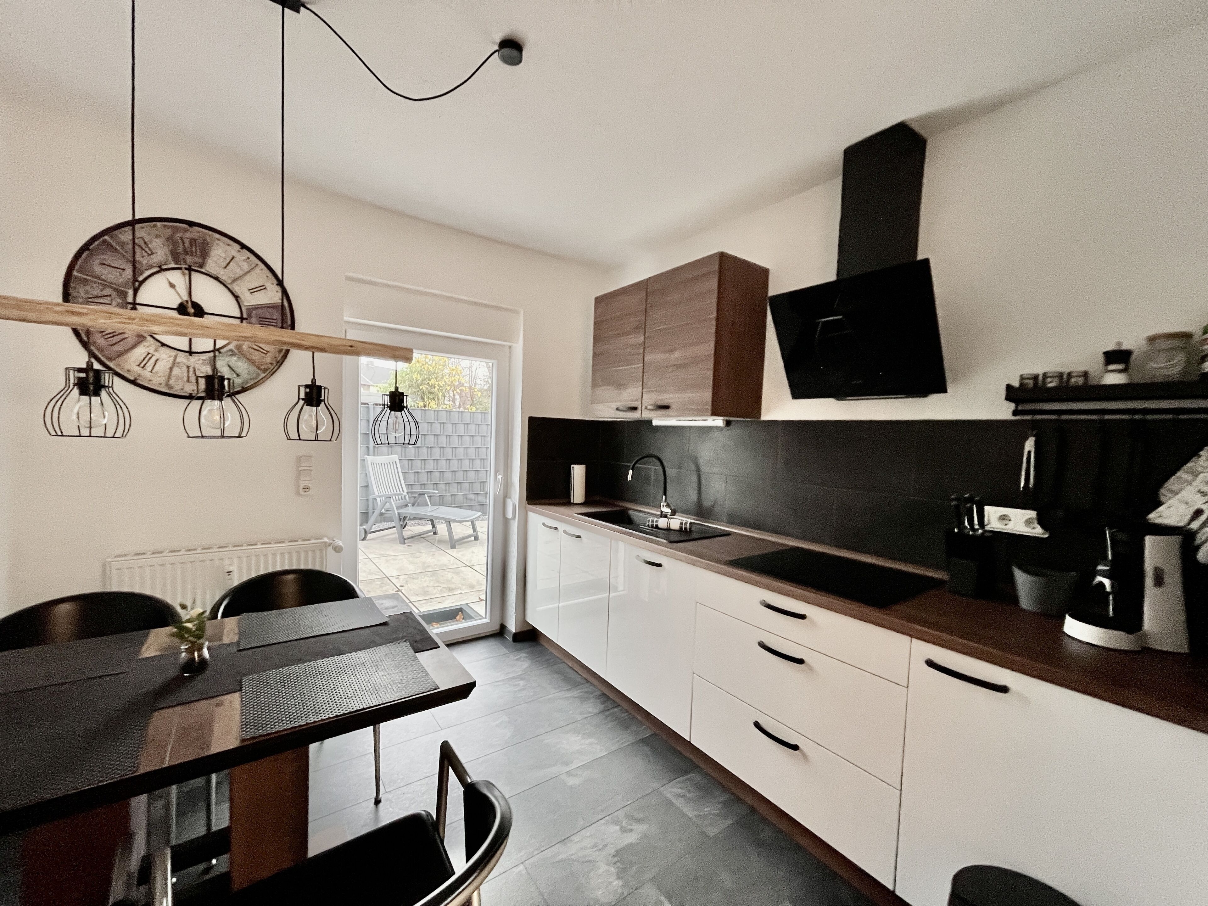 Una cocina moderna con armarios blancos, encimera negra y un reloj de pared grande.