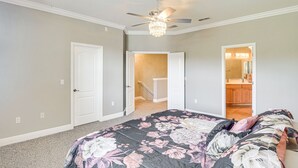 Ein Schlafzimmer mit einem großen Bett, einem Deckenventilator und Blick ins Badezimmer.