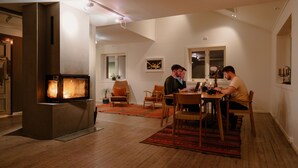 A modern dining area with a fireplace, wooden flooring, and a dining table with chairs. - In the middle of Lofoten! Unique and spacious dockside apartment. (STAMSUND)