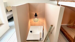 A room with a white wardrobe, a hanging light fixture, and a wooden floor. - In the middle of Lofoten! Unique and spacious dockside apartment. (STAMSUND)