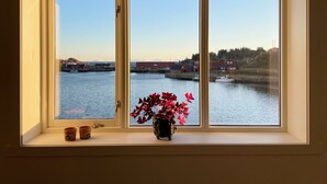 A window with a view of a calm river, buildings, and a clear sky. - In the middle of Lofoten! Unique and spacious dockside apartment. (STAMSUND)