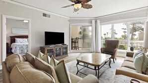 Un salón amplio con ventilador de techo, televisor de pantalla plana, mesa de comedor y sofá.