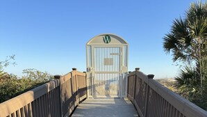 Un paseo marítimo de madera que conduce a una entrada con puerta y un logotipo.