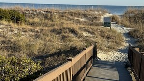 Un paseo marítimo de madera que conduce a una playa, con un letrero que indica una reserva natural.