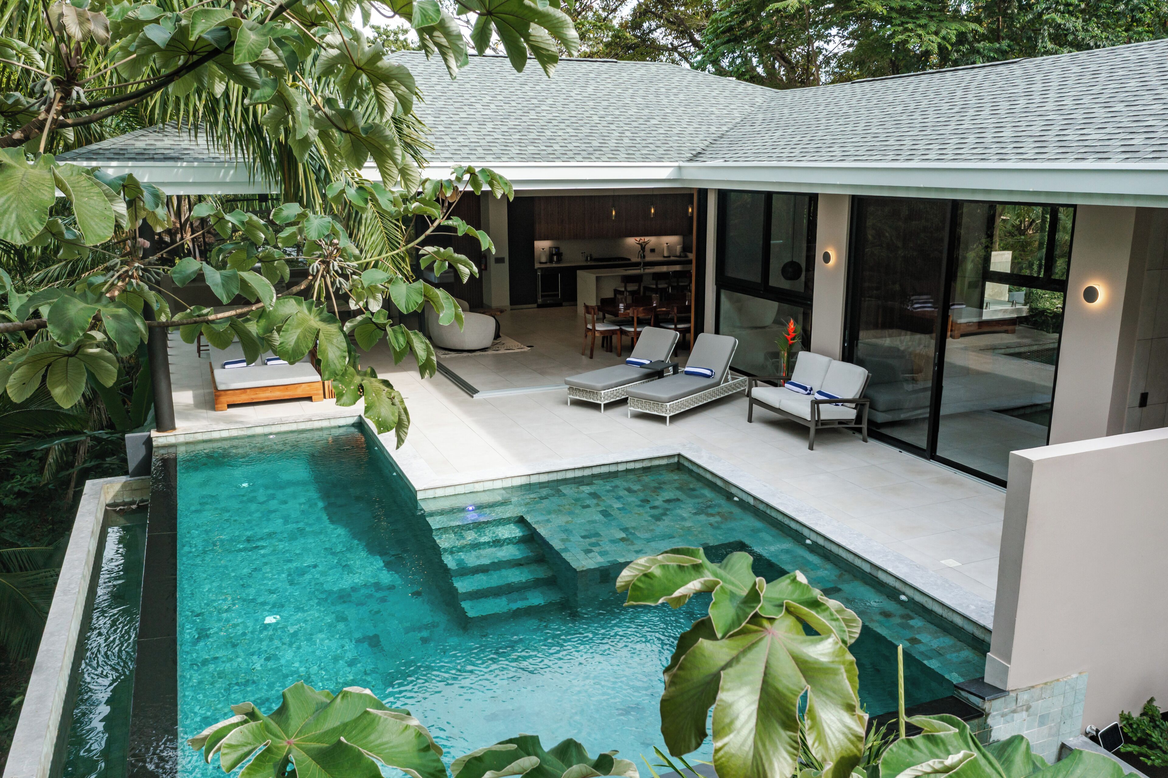A modern house with a swimming pool, a dining area, and a kitchen.