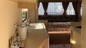 A compact RV kitchen with a sink, countertop, and cabinets. - Beach Vibes - Silver Beach - Basic (Skegness)