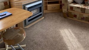 Interior compacto de una autocaravana con kitchenette, comedor y zona de estar con un sofá estampado.