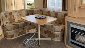 Interior compacto de una caravana con kitchenette, una mesa de comedor y un sofá.