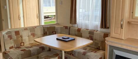 A compact RV interior with a kitchenette, a dining table, and a sofa.